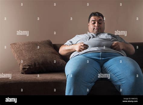 fat man on sofa|obese man sitting.